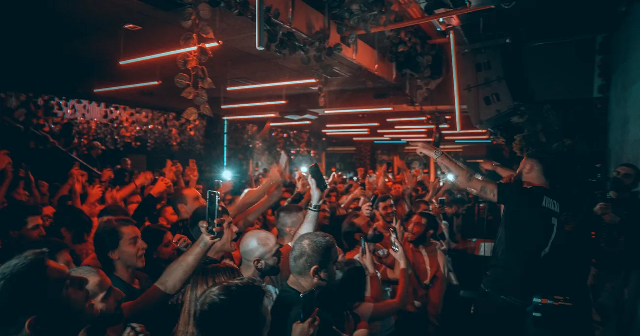 Peak-hour birthday crowd under red lights at Sakhelosno Tbilisi